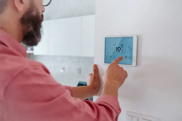 Homeowner Adjusting Smart Thermostat For Indoor Heating And Cooling Control