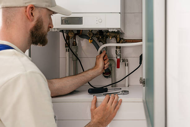 Heating Technician Servicing Wall Mounted Boiler System During Maintenance